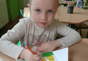 Dziewczynka z grupy 2 wykonuje kartkę wielkanocną.