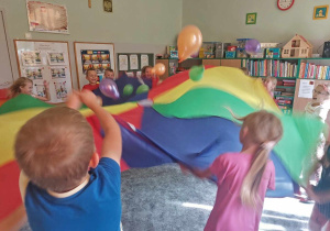 Dzieci z grupy 1 podczas zabawy z chustą animacyjną i kolorowymi balonami