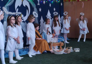 Dziewczynka z grupy 1, przebrana za Maryję, śpiewa kolędę podczas występu świątecznego