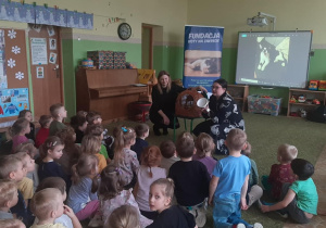 Dzieci siedzą na dywanie i słuchają pogadanki przeprowadzonej przez pracowników fundacji