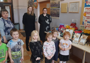 Dzieci i pracownicy fundacji stojący obok stolika, na którym znajduje się karma