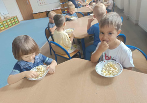Dzieci jedzące przy stoliku popcorn