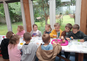 Dzieci przy stoliku wykonują pracę plastyczną