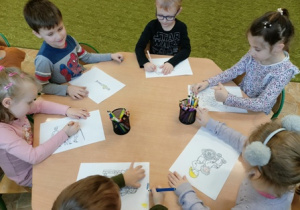 Dzieci z grupy 2 kolorują kredkami obrazki.