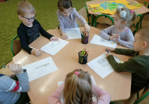Dzieci z grupy 2 kolorują kredkami obrazki.