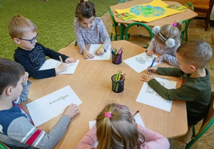 Dzieci z grupy 2 kolorują kredkami obrazki.