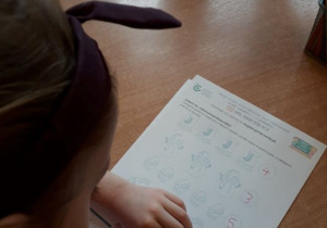 Dziewczynka z grupy 8 wykonująca pracę dotyczącą ,,Bezpiecznych ferii".