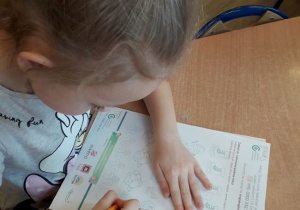 Dziewczynka z grupy 8 wykonująca pracę dotyczącą ,,Bezpiecznych ferii".