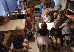 Dzieci z grupy 6 siedzące przy stolikach tuż przed przedstawieniem.