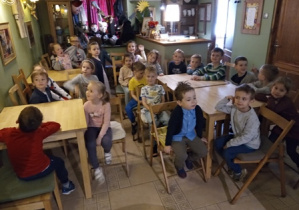 Dzieci z grupy 2 siedzące przy stolikach tuż przed przedstawieniem.