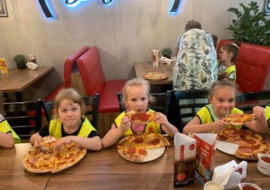 Dziewczynki z grupy 2 jedzą pizzę.