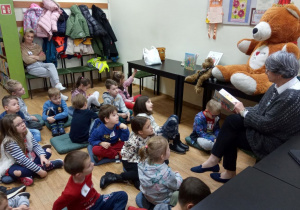 Dzieci w bibliotece podczas słuchania bajki czytanej przez panią bibliotekarkę