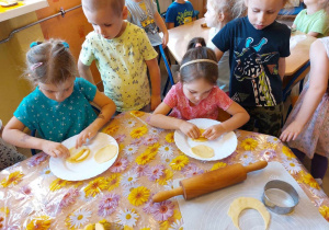 Dziewczynki kładą pokrojone jabłka na ciasteczka