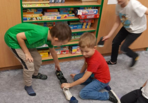 Chłopcy ustawiają buty na dywanie, jeden za drugim