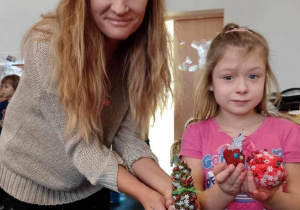 Dziewczynka z mamą prezentują wykonane przez siebie dekoracje na choinkę