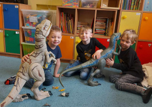 Chłopcy bawią się dużymi, zabawkowymi dinozaurami