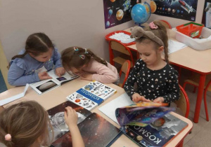 Dzieci oglądają książki o kosmosie siedząc przy stoliku
