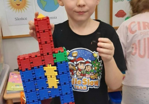 Chłopiec prezentuje rakietę kosmiczną zbudowaną z klocków