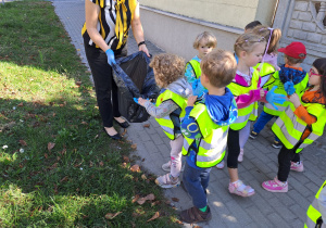 Dzieci z grupy 2 sprzątają śmieci na terenie przedszkola.