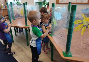Dzieci malujące farbą kwiaty na folii