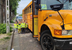 Grupa przedszkolna obok żółtego szkolnego autobusu