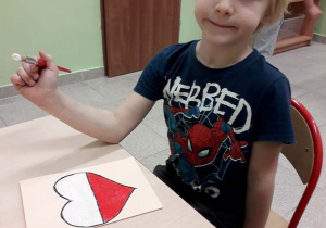 Chłopiec z grupy 4 maluje farbami serce dla Powstańców Warszawskich.