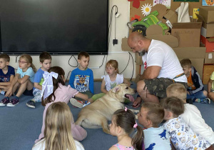 Pies leżący wśród dzieci na dywanie