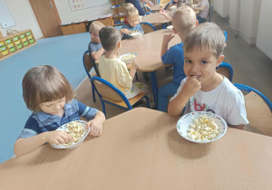 Dzieci jedzące przy stoliku popcorn