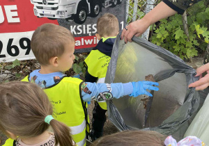 Dzieci w rękawiczkach jednorazowych zbierające śmieci do worka