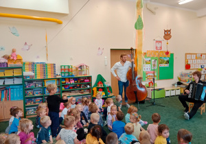 Dzieci w sali przedszkolnej i patrzą na muzyków
