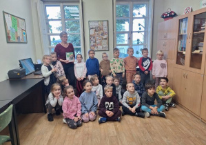 Zdjęcie grupowe w bibliotece dzieci i pracownika biblioteki