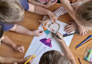 Dzieci robiące wspólną pracę plastyczną przy stoliku