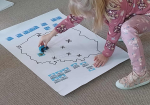 Dziewczynka z grupy 7 umieszcza symbol na mapie.