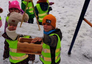 Dzieci sypiące karmę do karmika
