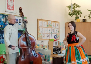 Grupa muzyków wraz z tancerką występująca w sali przedszkolnej przed dziećmi