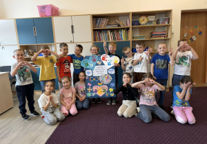 Grupa dzieci prezentująca wspólna pracę plastyczną.