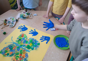 Grupa dzieci prezentująca wspólna pracę plastyczną.