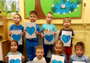 Grupa dzieci prezentująca wspólna pracę plastyczną.