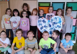 Grupa dzieci prezentująca wspólna pracę plastyczną.