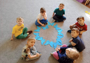 Grupa dzieci prezentująca wspólna pracę plastyczną.