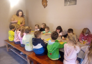 Dzieci przy stolikach wykonują pracę plastyczną.