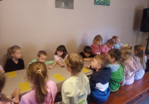 Dzieci przy stolikach wykonują pracę plastyczną.