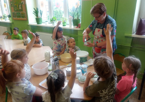 Dzieci siedzą przy stolikach i przygotowują babeczki.