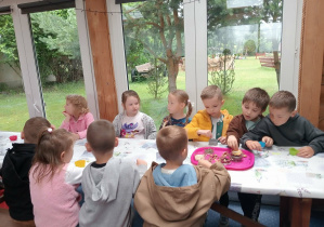 Dzieci przy stoliku wykonują pracę plastyczną