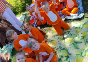 Dzieci przebrane w stroje siedzą razem na kocu