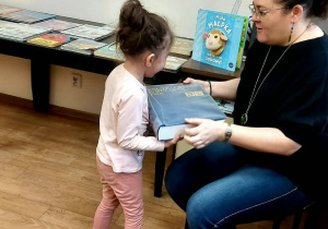 Dziecko przynosi książkę pani bibliotekarce