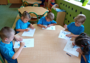 Dzieci z grupy 5 podczas kolorowania niebieskich motyli.