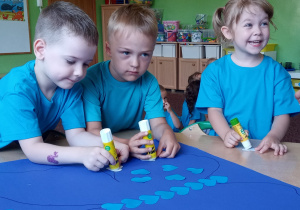 Dzieci z grupy 2 podczas wyklejania motyla niebieskimi serduszkami.