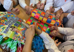 Zdjęcie przedstawia ręcę dzieci z kciukami wskazującymi, że prezenty są ok.