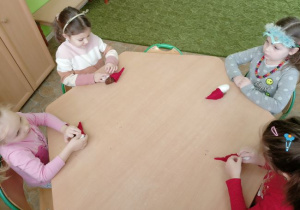 Dzieci z grupy 2 podczas konstruowania małego Mikołaja z szyszki.